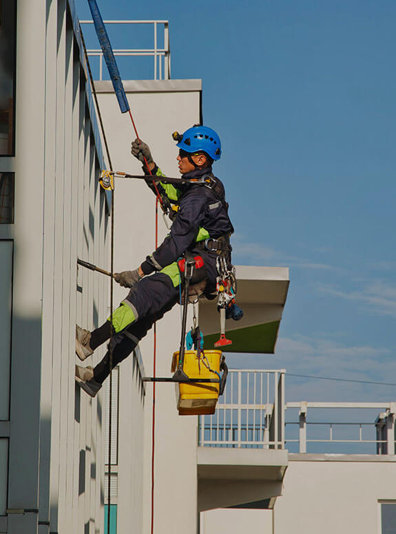 Homme suspendu à un bâtiment avec un harnais de sécurité